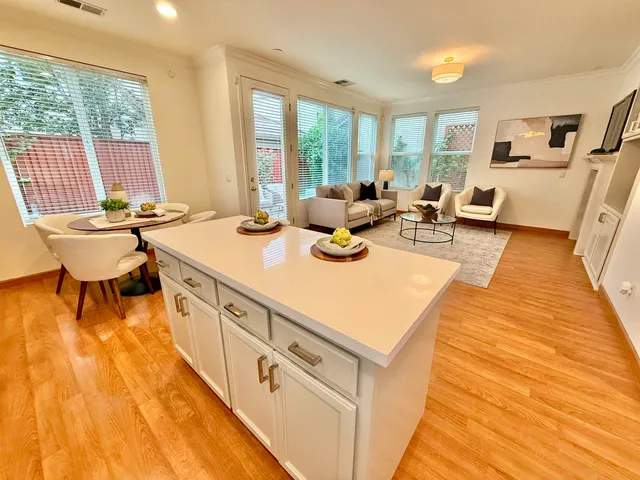a view of a kitchen with kitchen island a large window cabinets a sink and stainless steel appliances
