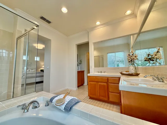 a bathroom with a sink double vanity granite tub shower and a mirror
