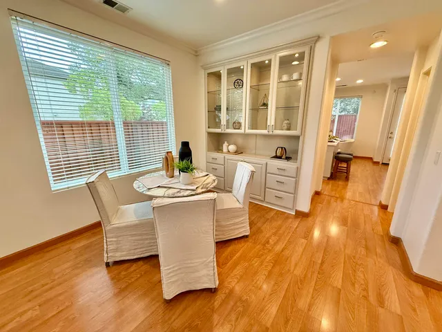 a dining room with wooden floor and large windows