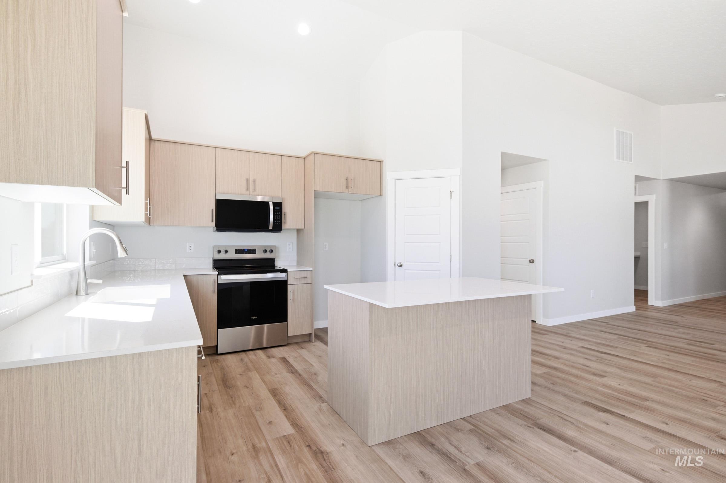 12817 Decatur Street Nampa, ID 83651 - Photo 5 of 19 Bright kitchen featuring wood-finish cabinetry, stainless steel appliances, a center island with countertop seating, and wood-finish flooring