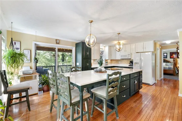 a kitchen with stainless steel appliances granite countertop a stove a refrigerator a kitchen island a dining table and chairs with wooden floor