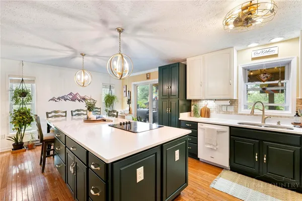 a kitchen with a stove a sink dishwasher and a dining table with wooden floor