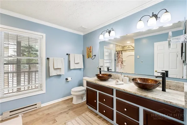 a spacious bathroom with double vanity a mirror a lamp and window