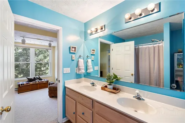 a spacious en suite bathroom with a double sink and mirror