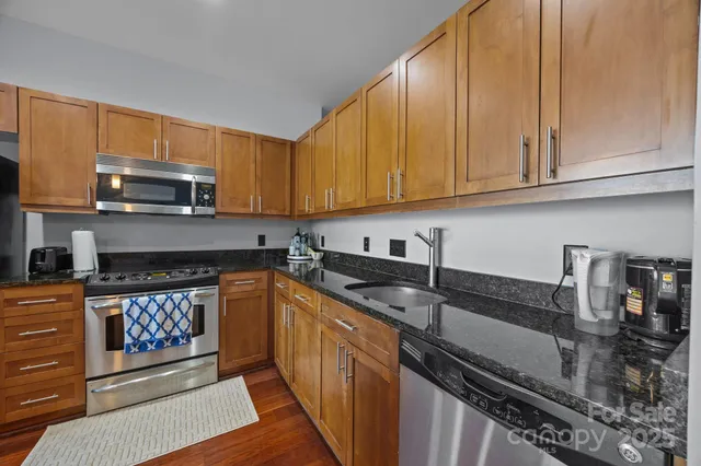 a kitchen with granite countertop a sink a stove and cabinets