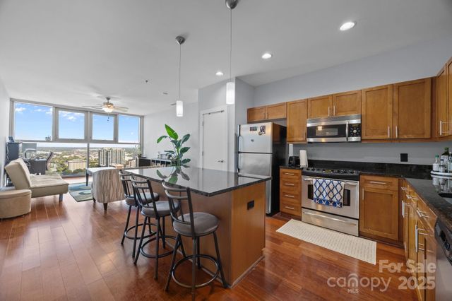 a kitchen with stainless steel appliances granite countertop a refrigerator a stove a sink a dining table and chairs with wooden floor