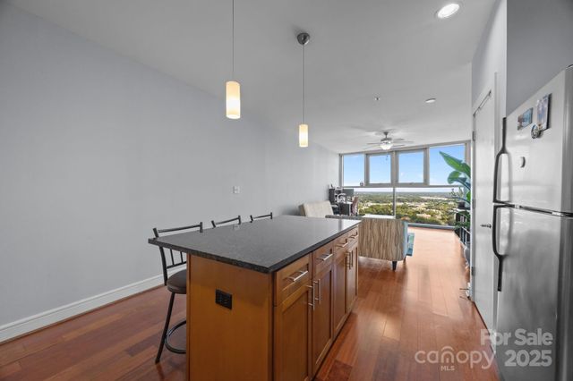 a kitchen with stainless steel appliances granite countertop a refrigerator a stove top oven a sink island and chairs