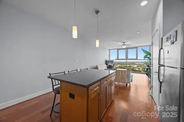 a kitchen with stainless steel appliances granite countertop a refrigerator a stove top oven a sink island and chairs