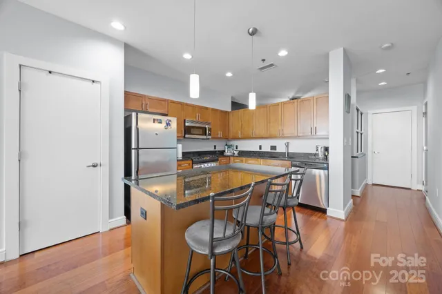 a kitchen with stainless steel appliances granite countertop a refrigerator a microwave oven a sink with island and chairs