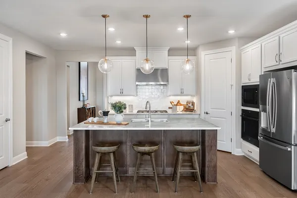 a kitchen with stainless steel appliances granite countertop a dining table chairs sink and refrigerator