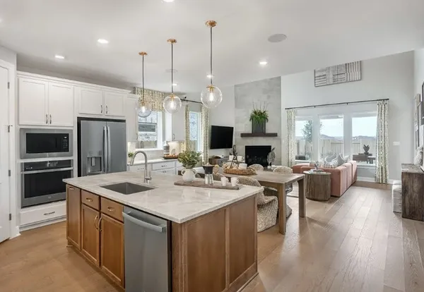 a kitchen with a stove a sink a kitchen island with couches and chairs