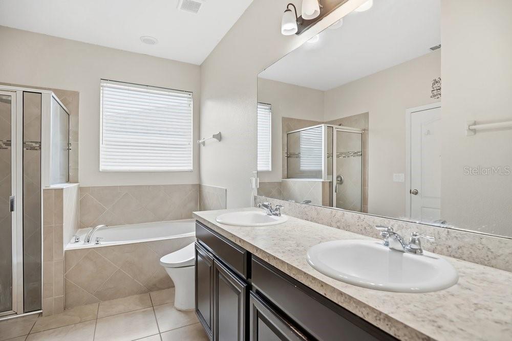680 Preakness Circle Deland, FL 32724 - Photo 12 of 28 a bathroom with a granite countertop sink a mirror a bathtub and next to a window