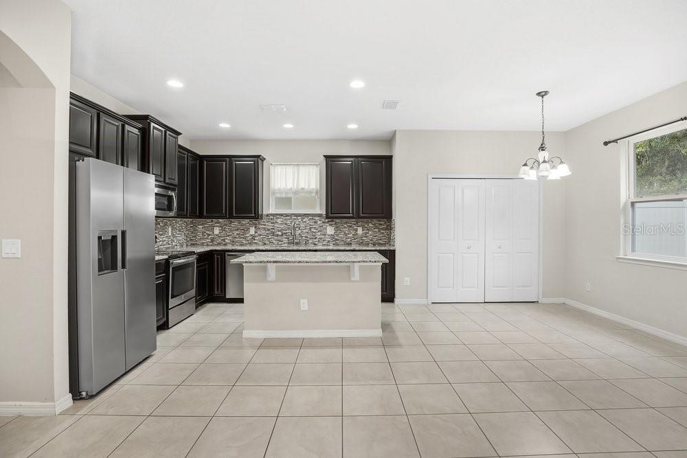 680 Preakness Circle Deland, FL 32724 - Photo 8 of 28 a large kitchen with granite countertop a stove a sink dishwasher a refrigerator and white cabinets with wooden floor