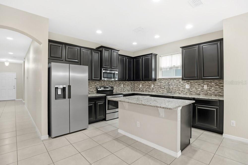 680 Preakness Circle Deland, FL 32724 - Photo 9 of 28 a kitchen with stainless steel appliances granite countertop a stove a sink and a refrigerator