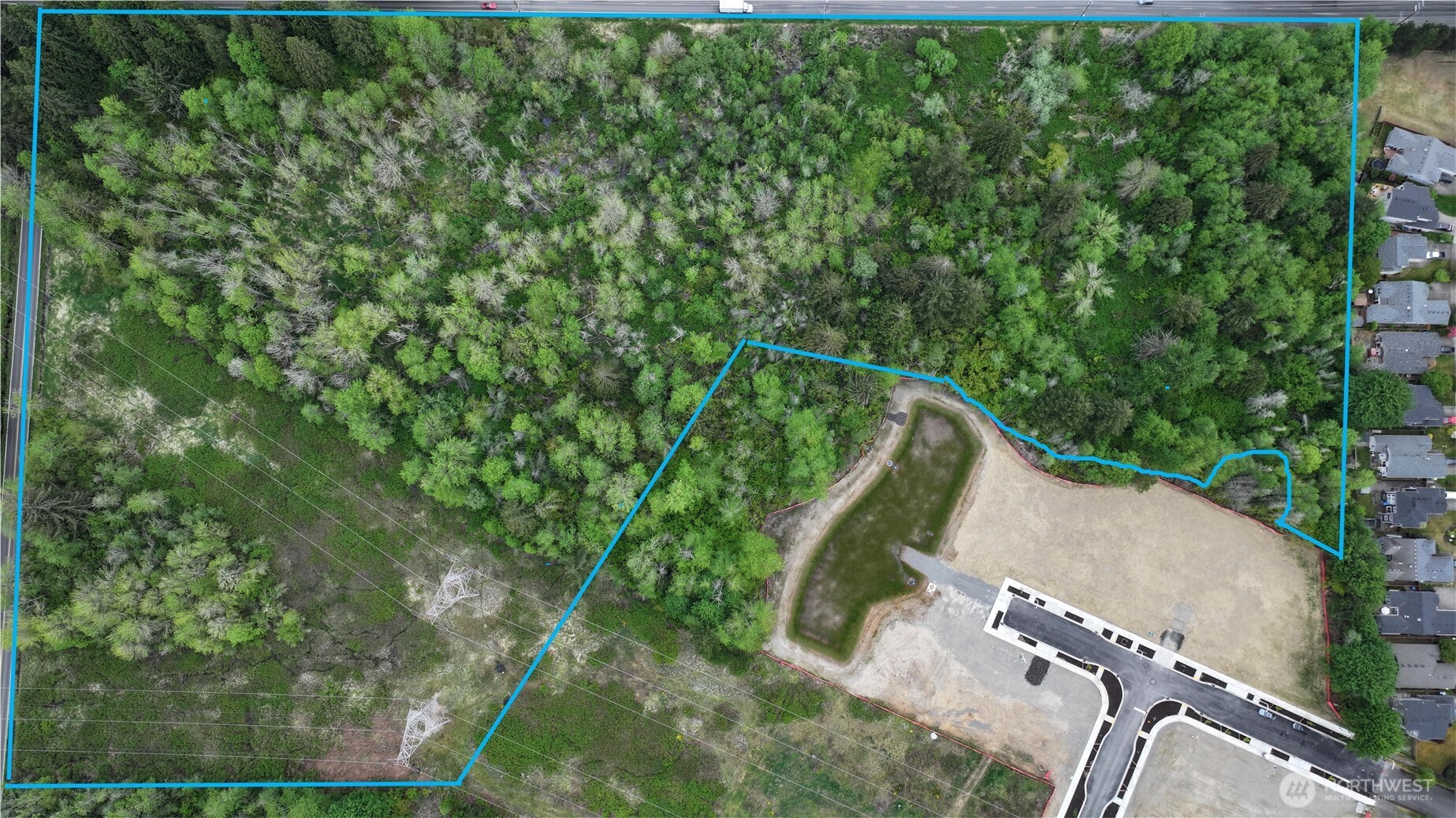 an aerial view of a residential houses with outdoor space and trees all around