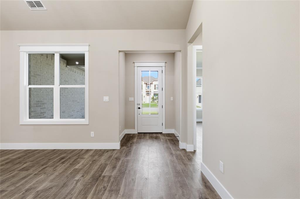 709 Anne Road Van Alstyne, TX 75495 - Photo 3 of 28 Interior entry area featuring wood-finish flooring, light neutral wall tones, white baseboards, and a white paneled door with glass inserts