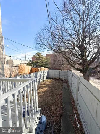 a view of a backyard with wooden fence and large trees
