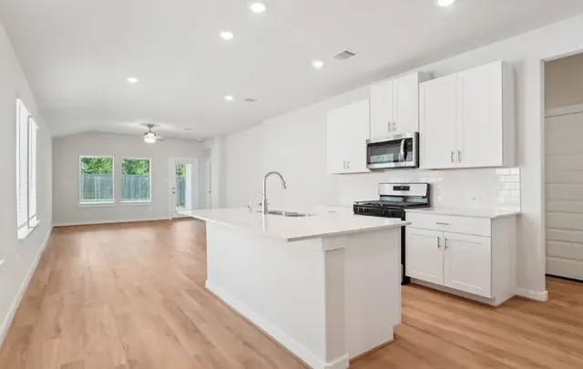 a kitchen with sink a microwave and cabinets