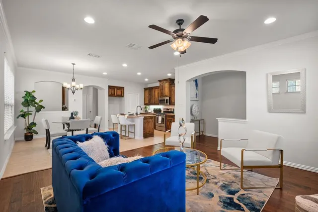 a living room with furniture kitchen view and a chandelier