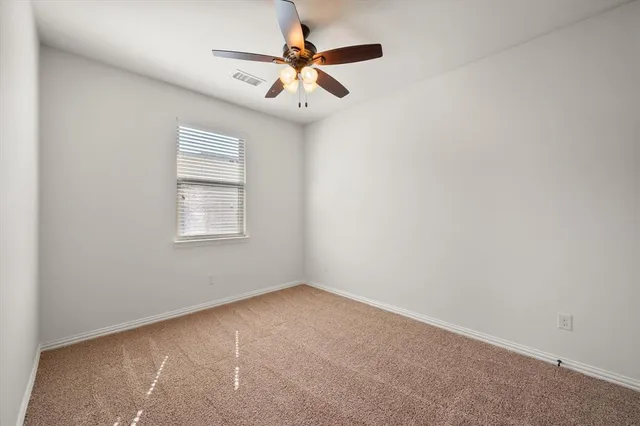 an empty room with a window and a ceiling fan