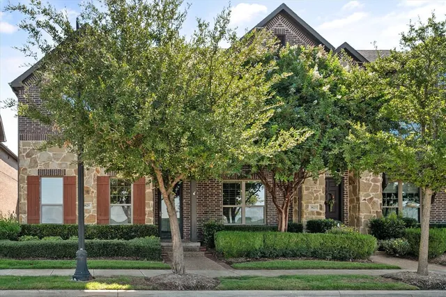 a front view of a house with garden and trees