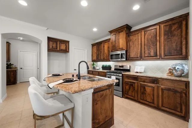 a kitchen with stainless steel appliances granite countertop a stove a sink dishwasher a microwave oven and a refrigerator with wooden cabinets