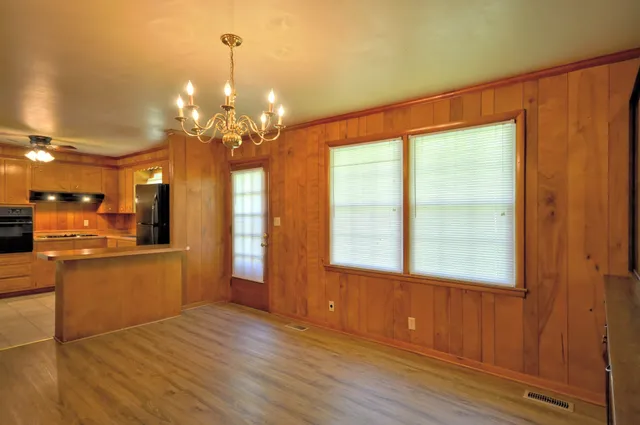 a kitchen with stainless steel appliances granite countertop a refrigerator a sink dishwasher a dining table and chairs with wooden floor