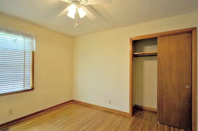 a view of empty room with wooden floor and fan