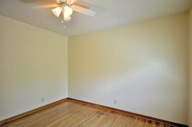 an empty room with wooden floor and fan