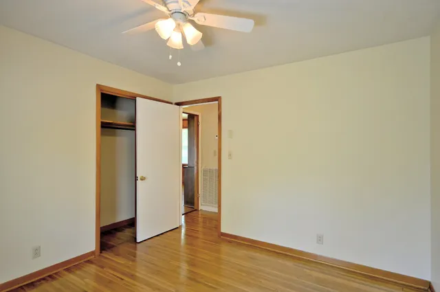 an empty room with wooden floor and a ceiling fan