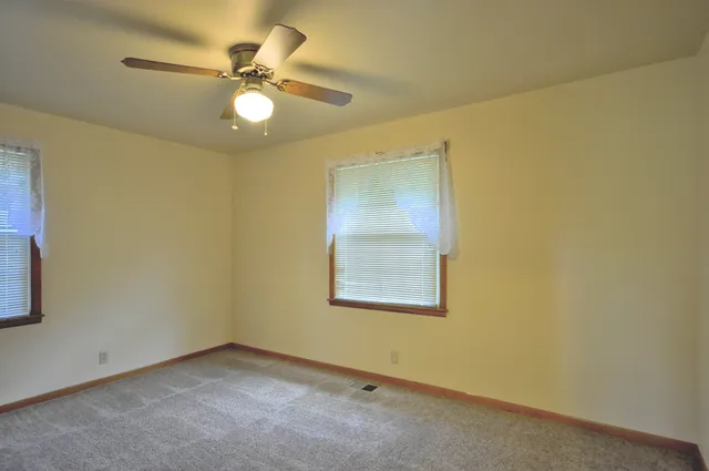 an empty room with a ceiling fan and a window