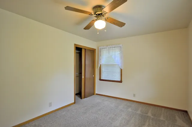 an empty room with a window and a ceiling fan