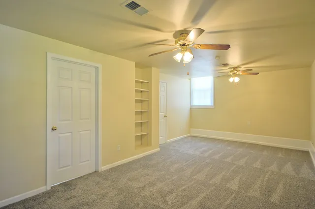 an empty room with a window and a fan