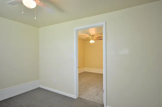 an empty room with a window and a ceiling fan