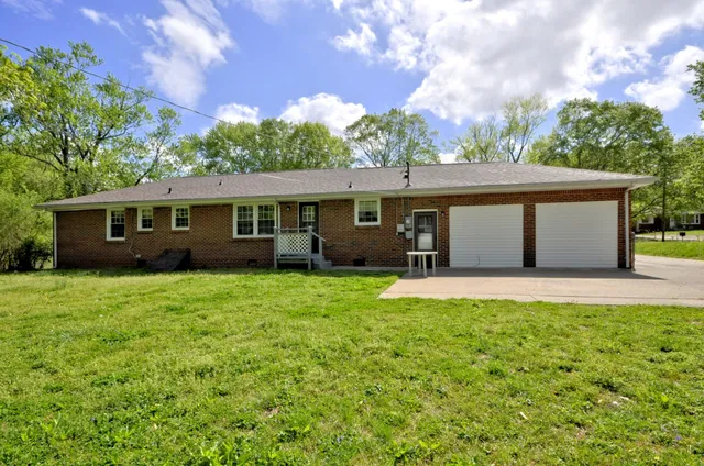 a view of a house with backyard and a tree