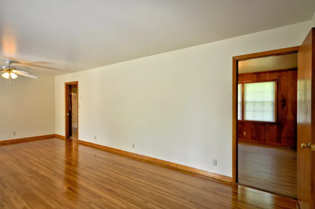 a view of an empty room with wooden floor and a mirror