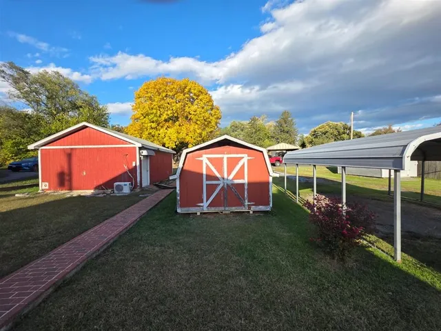 a view of a tiny house with a big yard and large trees