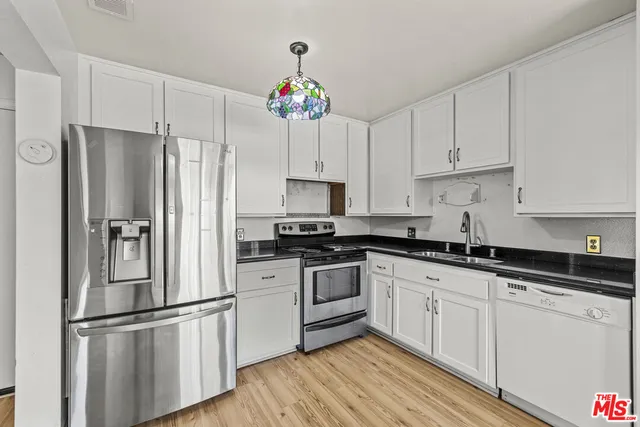 a kitchen with granite countertop a refrigerator cabinets and wooden floor