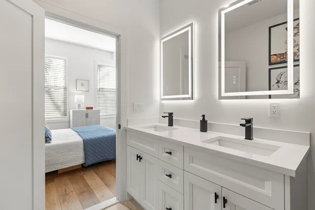 a en suite bathroom with a double vanity sink a mirror and next to a window