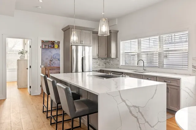 a kitchen with stainless steel appliances granite countertop a sink a stove a refrigerator a dining table and chairs