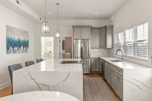 a large kitchen with stainless steel appliances kitchen island granite countertop a refrigerator a sink dishwasher a dining table and chairs with wooden floor