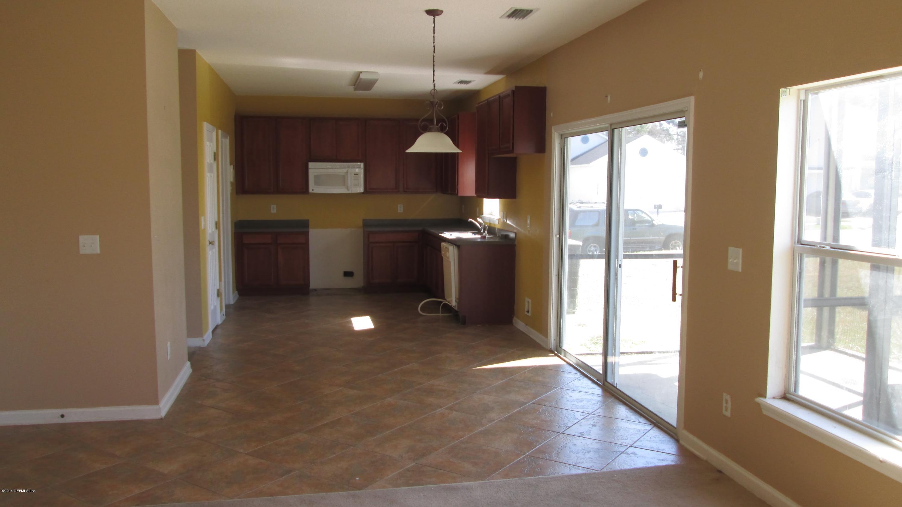 7201 Rampart Ridge Circle West Jacksonville, FL 32244 - Photo 4 of 14 a kitchen with stainless steel appliances granite countertop a refrigerator a sink dishwasher a stove and a dining table with wooden floor