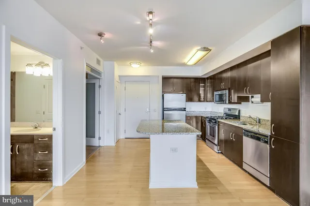 a large kitchen with stainless steel appliances kitchen island a large counter top a stove and a refrigerator