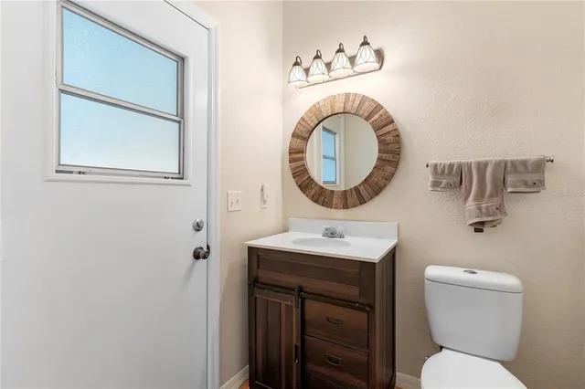 a bathroom with a toilet sink vanity and mirror