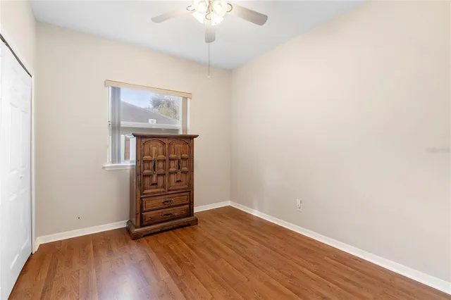 an empty room with wooden floor closet and windows