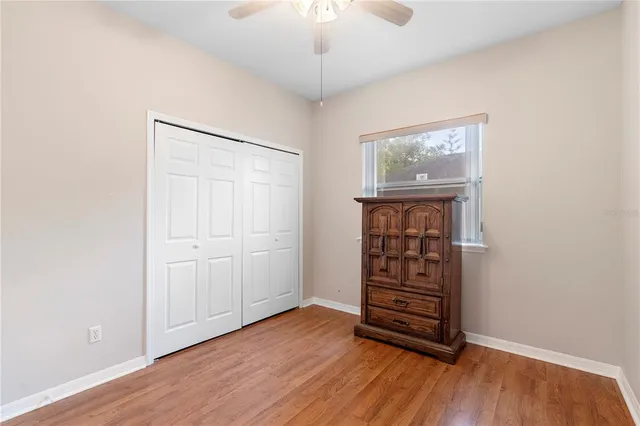 an empty room with wooden floor closet and windows