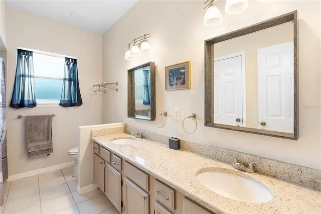 a bathroom with a granite countertop double vanity sink and a mirror