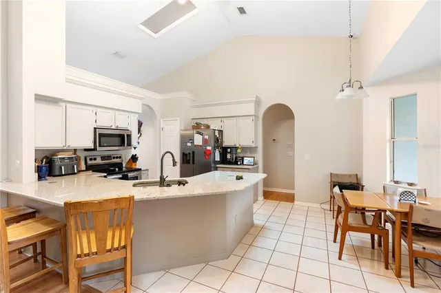 a kitchen with stainless steel appliances granite countertop a stove top oven a sink dishwasher and white cabinets with wooden floor