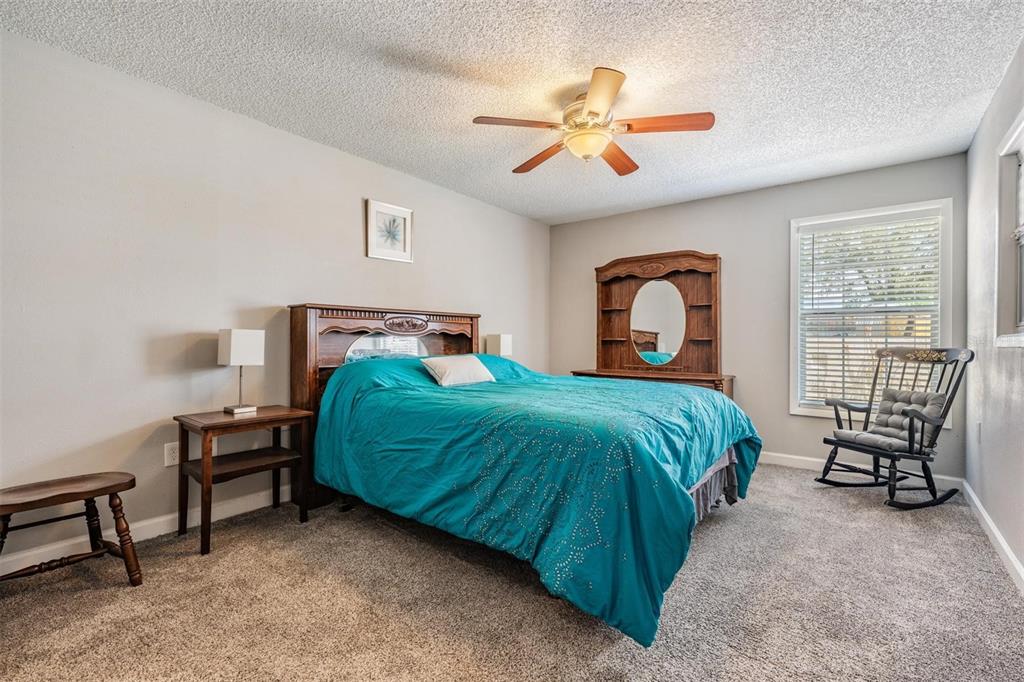 11308 Versailles Lane, Unit C Port Richey, FL 34668 - Photo 15 of 33 a bedroom with a bed and a chandelier