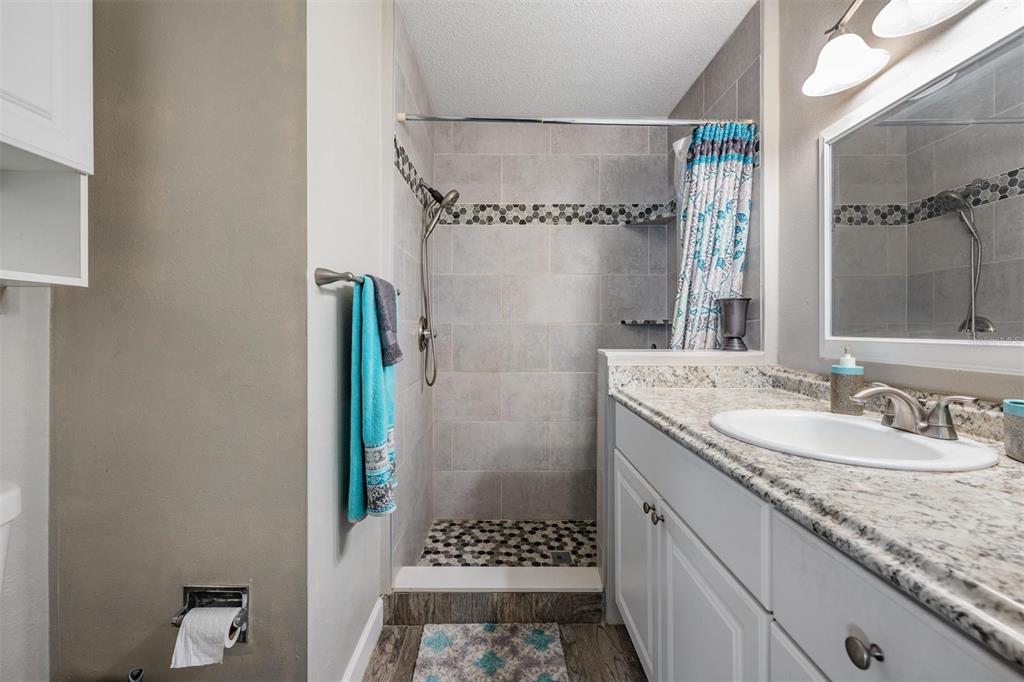 11308 Versailles Lane, Unit C Port Richey, FL 34668 - Photo 17 of 33 a bathroom with a granite countertop sink a toilet and shower
